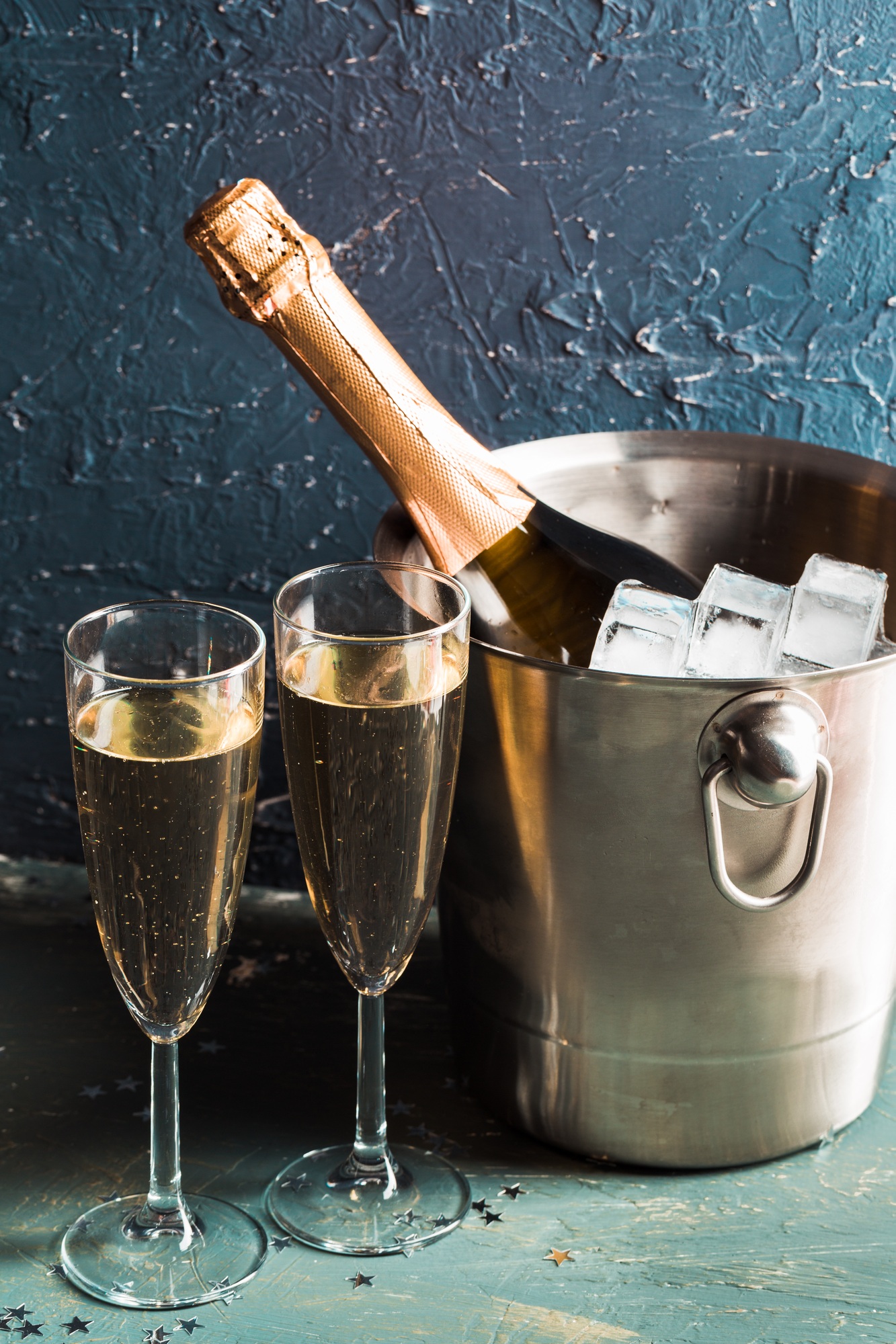 Champagne bottle in bucket with ice and glasses of champagne